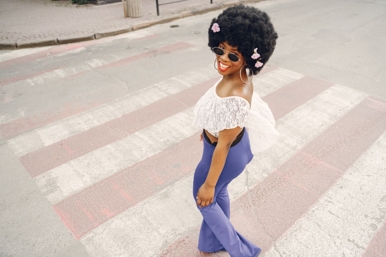 test-01 Fashionable woman in sunglasses and floral afro hair walking confidently on a crosswalk, exuding style and joy.