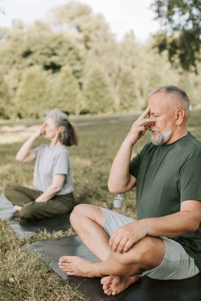 work-03 Elderly man and woman practicing yoga outdoors, promoting relaxation and healthy lifestyle.
